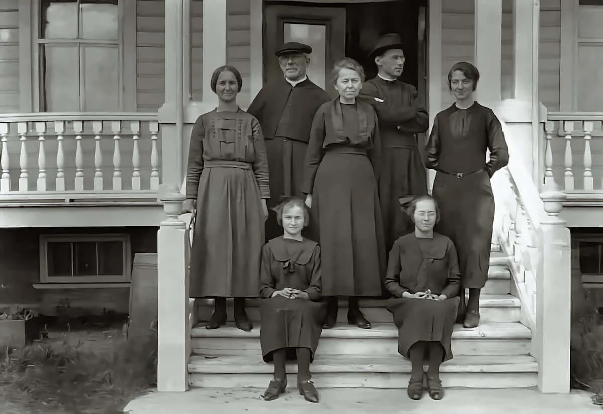 Mons. Labrie, el padre Ledoré y varias mujeres y niñas frente a una casa